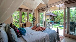 Ein Schlafzimmer mit Baldachinbett, Schreibtisch und Blick auf einen üppigen Garten.