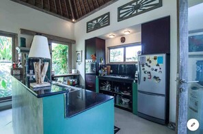 Une cuisine moderne dotée d’un îlot central, d’appareils électroménagers intégrés et offrant une vue sur l’extérieur.