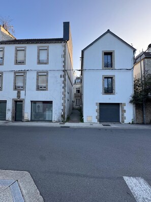 Et gadesyn med to hvide bygninger, hvoraf den ene har en garageport og den anden en balkon.