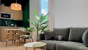 A modern living room with a grey sofa, a round coffee table, and a dining area with a wooden table and chairs. - Wellness Suite with Jacuzzi & Sauna, Premium Comfort in City Center (Quimper)