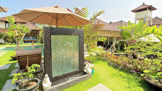 A well-maintained garden with a central decorative panel, a pool, and a covered seating area. - Hibiscus/Upper Suite/Ubud/Pool/AC (Bali)