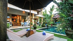 A poolside area with wicker lounge chairs, a small pool, and surrounding greenery. - Hibiscus/Upper Suite/Ubud/Pool/AC (Bali)