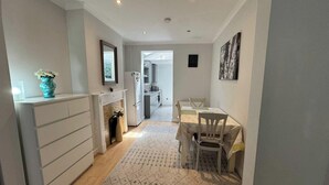 Une cuisine moderne avec des meubles blancs, un four encastré et un coin repas comprenant une table et des chaises.