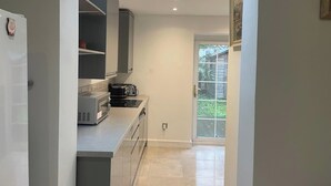 La cuisine est équipée d’un four, d’un micro-ondes et d’un grille-pain encastrés. Une porte-fenêtre coulissante donne accès à un balcon.