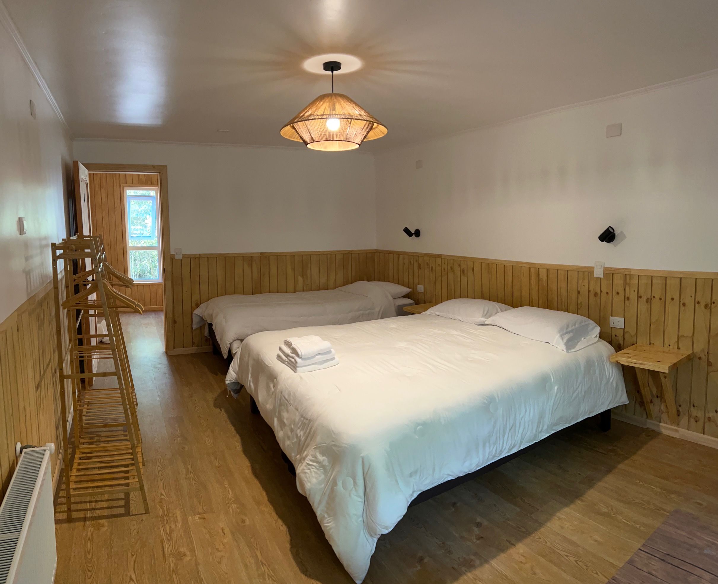 A room with two beds, a wooden ladder, a radiator, and a ceiling fan.