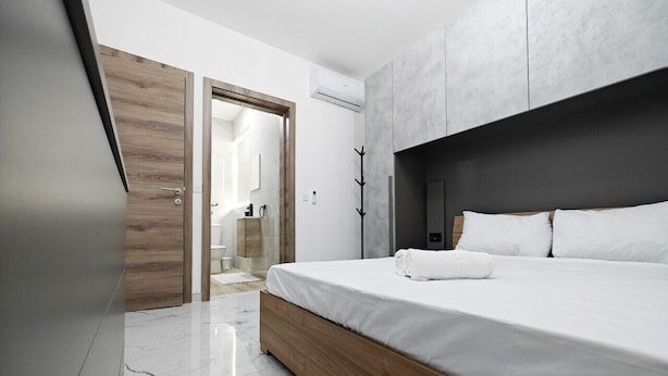Une chambre à coucher moderne avec un cadre de lit en bois, du linge de lit blanc et un grand miroir.