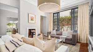 A modern living room with a sofa, coffee table, and a fireplace. - Bellevue House (Cape Town)