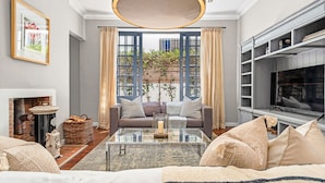 A modern living room with a fireplace, a sofa set, a coffee table, and a television. - Bellevue House (Cape Town)