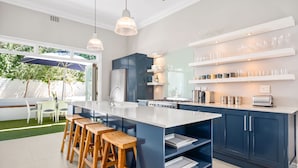 A modern kitchen with a large island, bar stools, and built-in appliances. - Bellevue House (Cape Town)