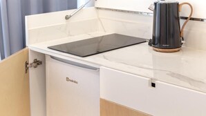 A kitchen with a built-in induction cooktop and a black electric kettle on the countertop. - Magnolia Suites & Stays (Porto)