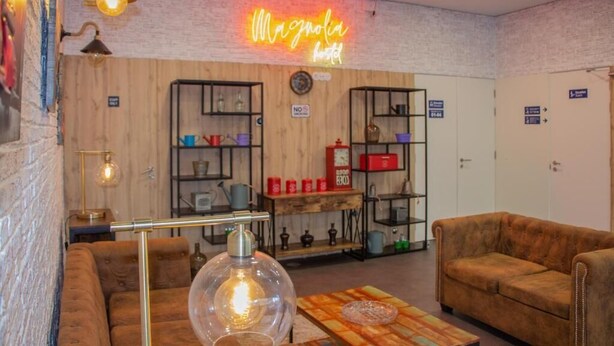 A cozy hotel lobby with a neon sign, wooden shelves, and a vintage lamp. - Magnolia Suites & Stays (Porto)