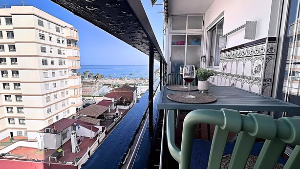 Een balkon met uitzicht op zee, een tafel met twee wijnglazen en een stoel.