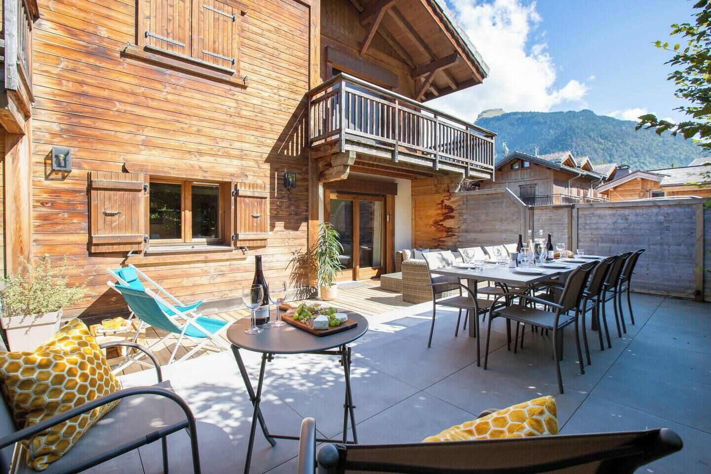 Una cabaña de madera con balcón, mobiliario exterior y vistas a la montaña.