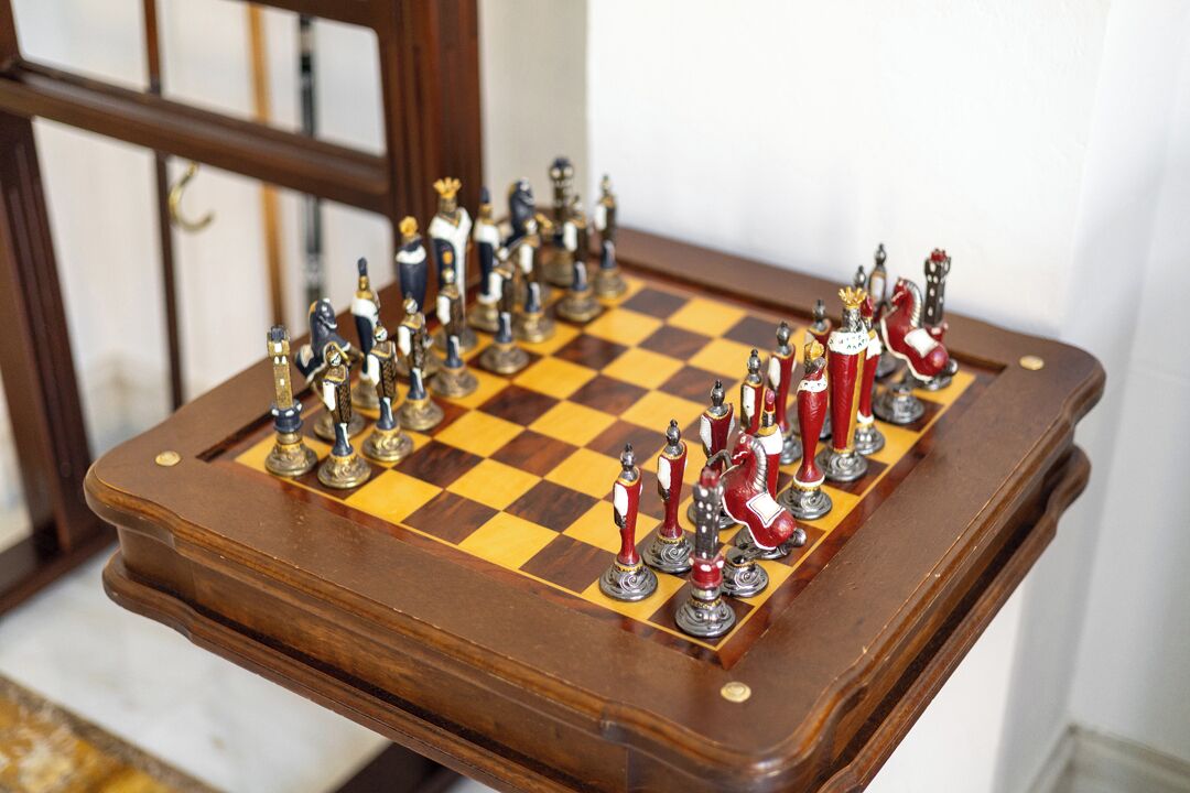 Een schaakbord met stukken op een houten tafel.