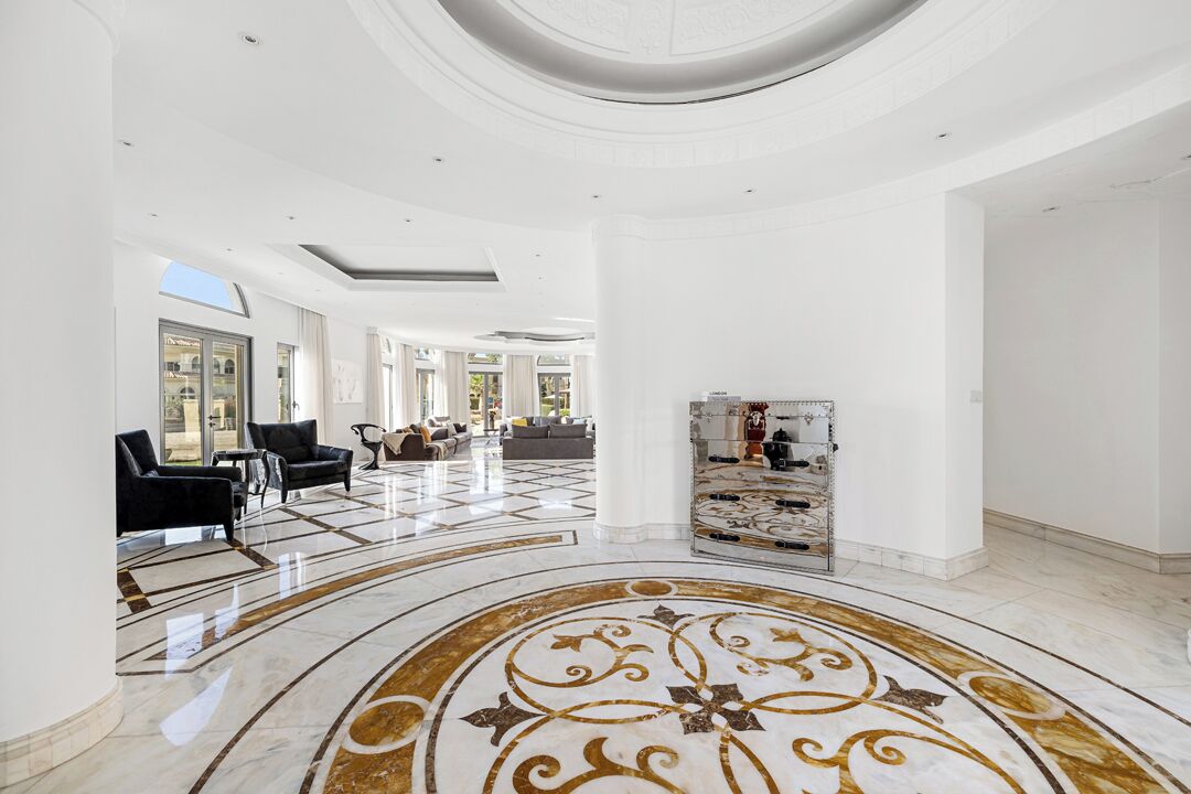 A spacious lobby with a marble floor, seating area, and a decorative column.