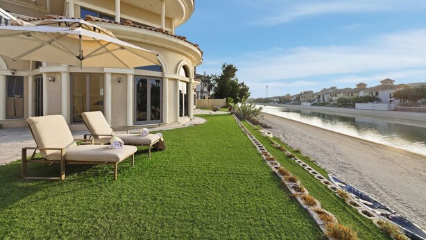 Uma villa moderna com piscina, área de estar externa e vista para a água.
