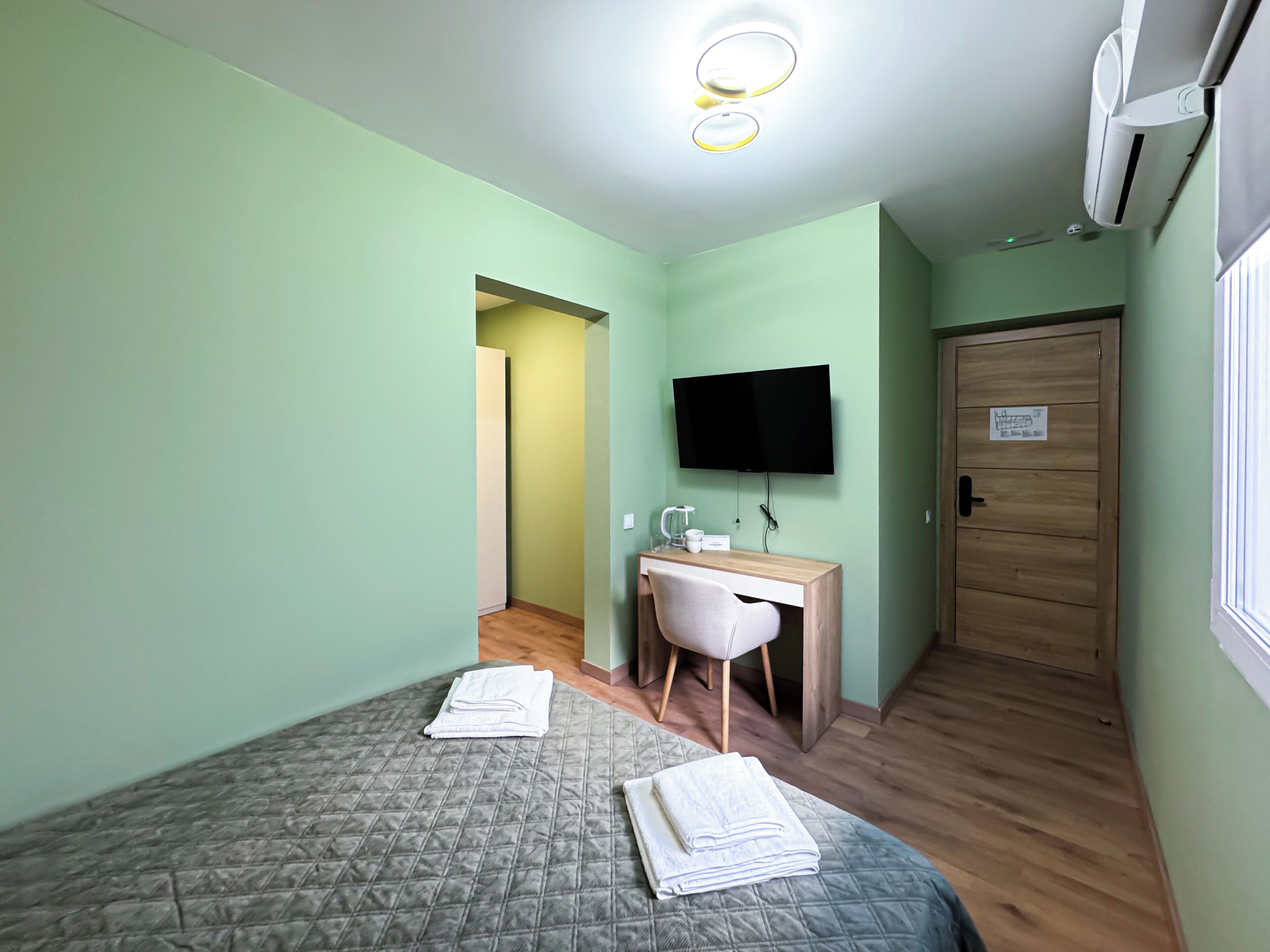 Una habitación con dos camas, un escritorio, una silla, un televisor y aire acondicionado.