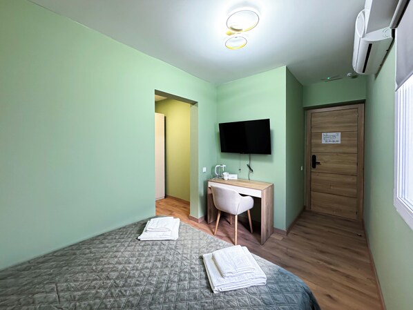 Une chambre avec deux lits, un bureau, une chaise, une télévision et un appareil de climatisation.