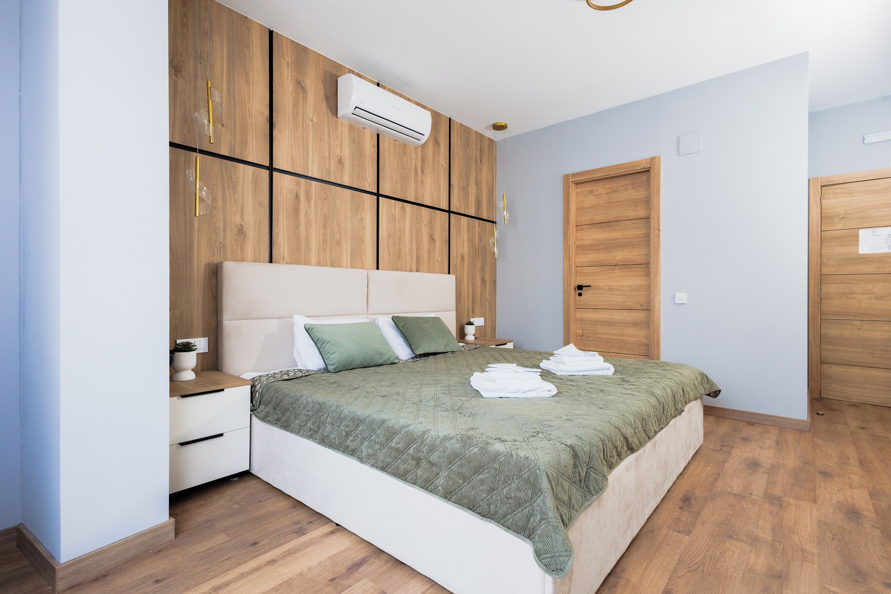 Un dormitorio con cama, armario de madera, mesitas de noche y aire acondicionado.
