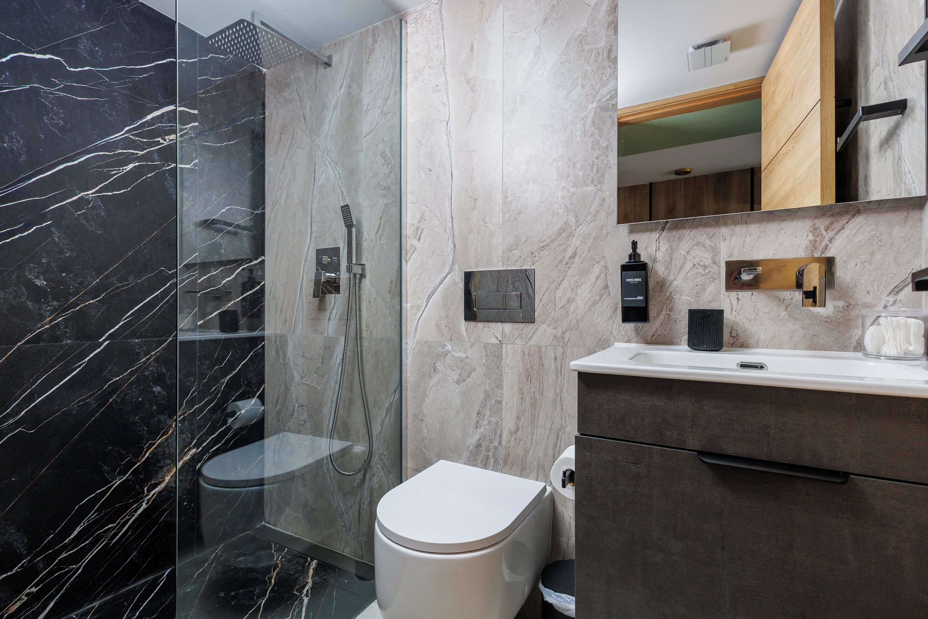 A modern bathroom with a glass-enclosed shower, a toilet, and a vanity with a mirror and sink.