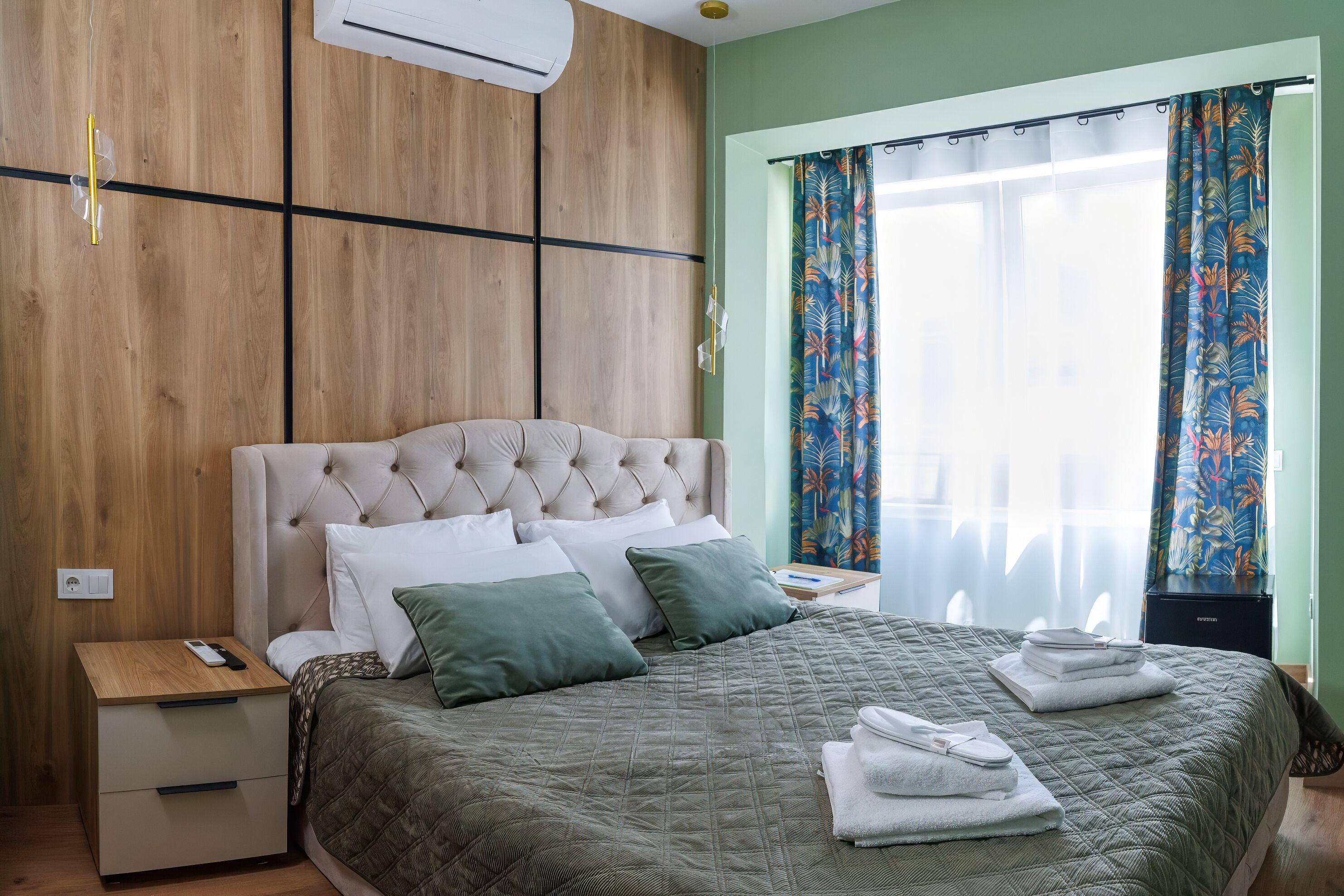 Ein Schlafzimmer mit Bett, Nachttisch und einem Fenster mit Vorhängen.