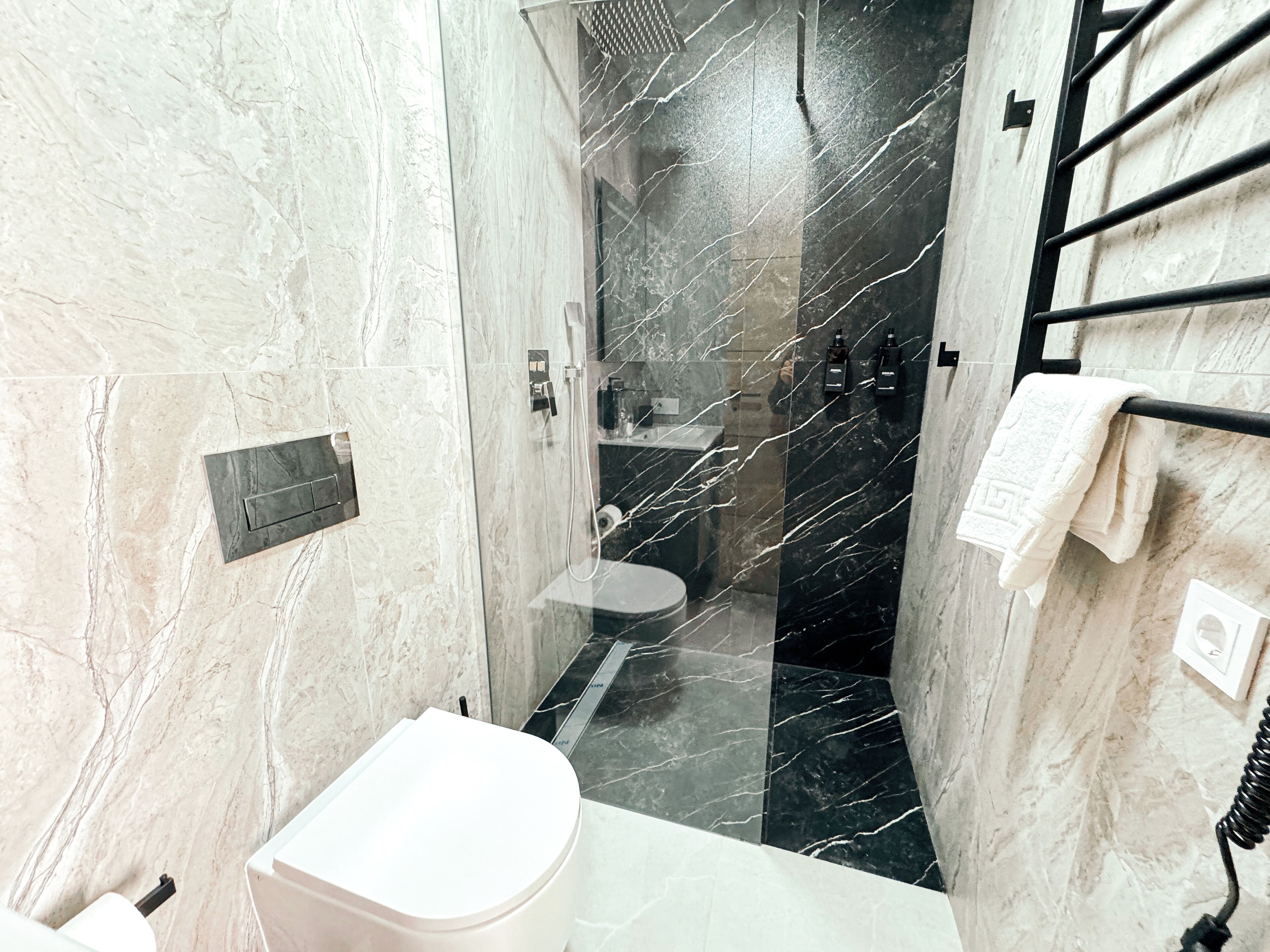 Une salle de bain équipée de toilettes, d’une douche et d’un porte-serviettes.