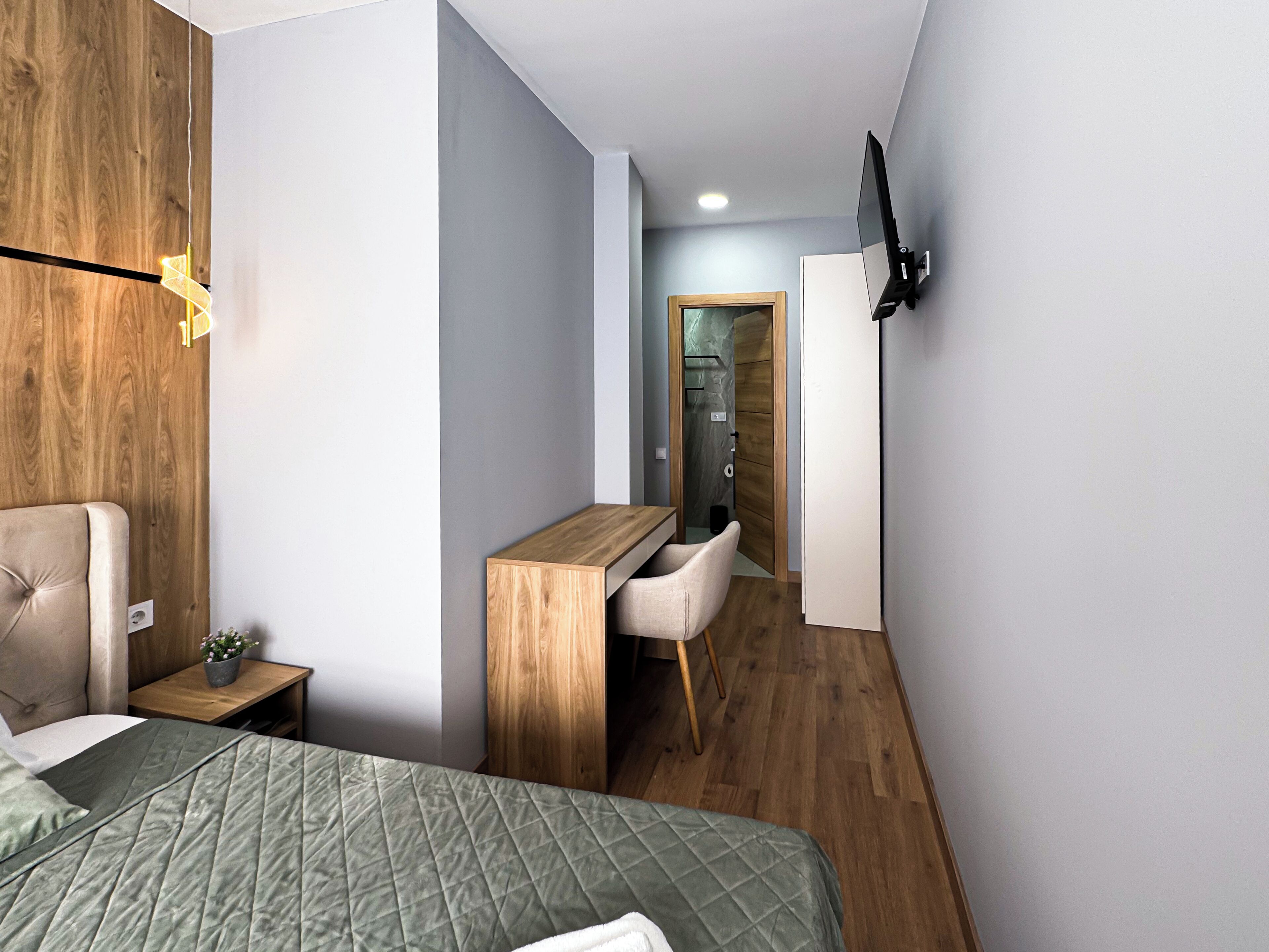Una camera da letto moderna con un letto, una scrivania e una TV.