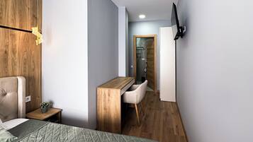 A modern bedroom with a bed, a desk, and a TV.