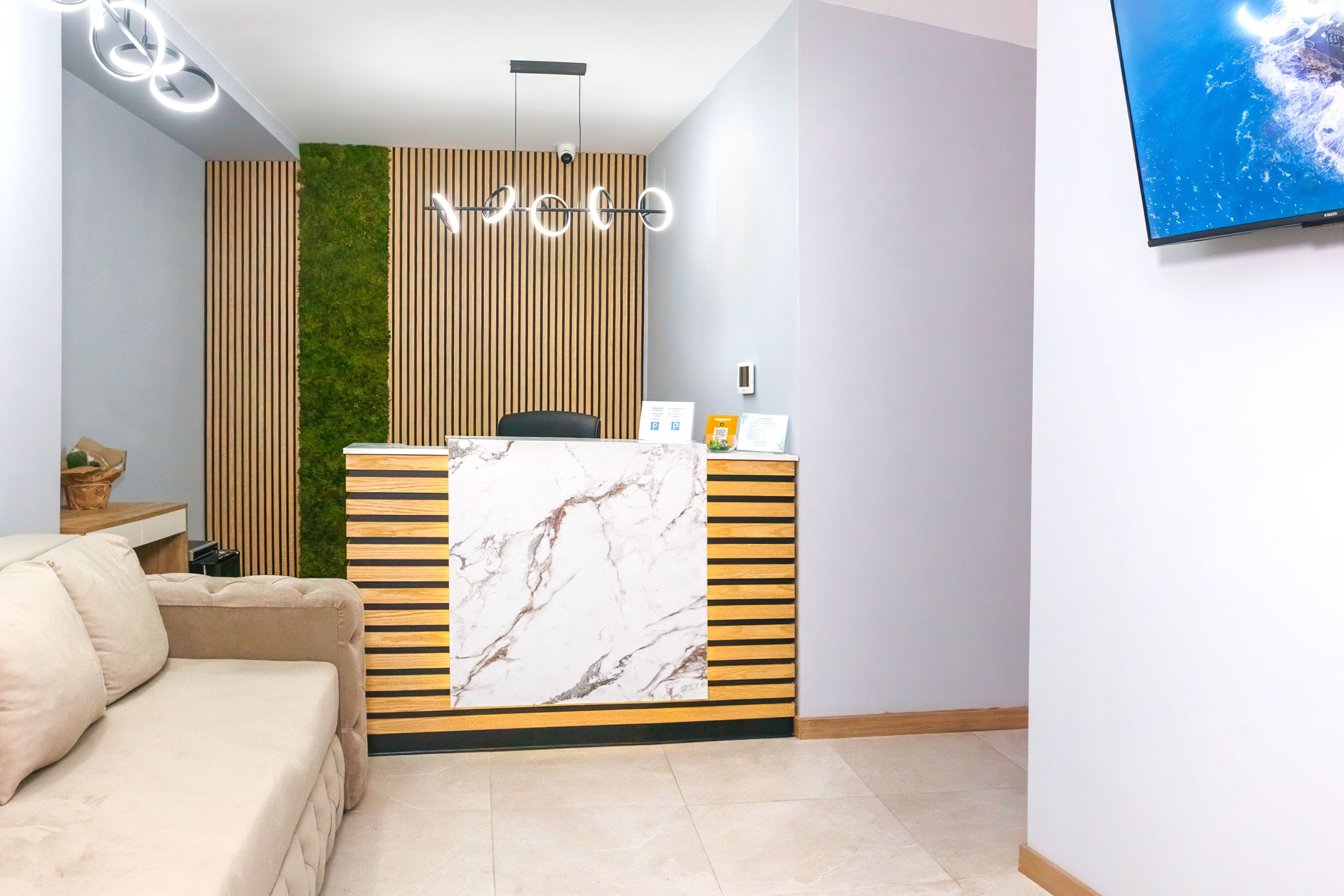 Tauleller de recepció amb frontal de marbre, jardí vertical verd i llum moderna.