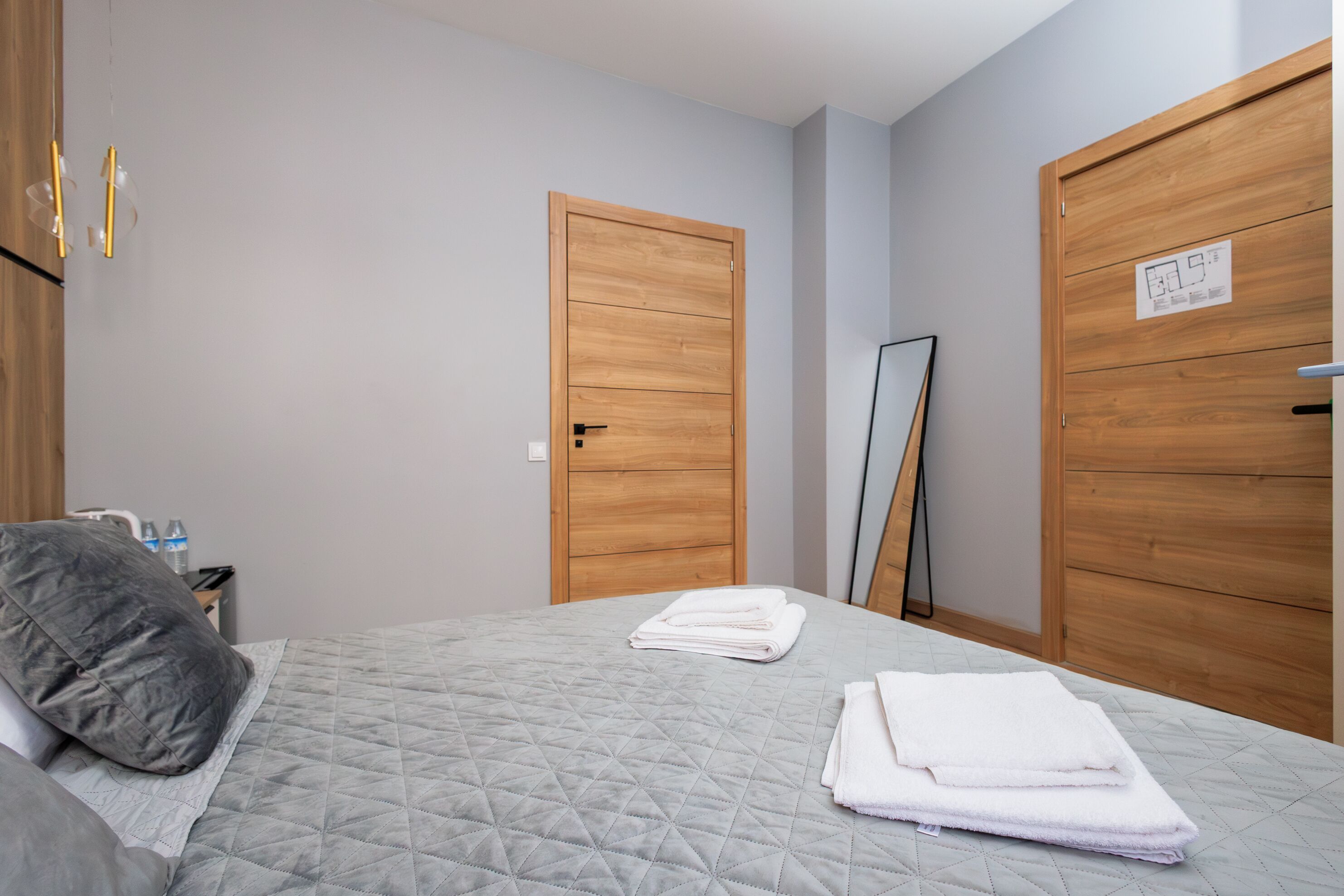 Une chambre à coucher avec un lit, une table de chevet, un miroir et des portes en bois.