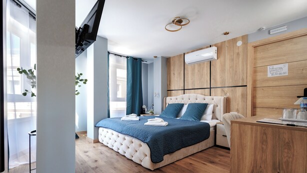Una camera da letto moderna con un letto grande, un armadio in legno, una scrivania e una televisione.