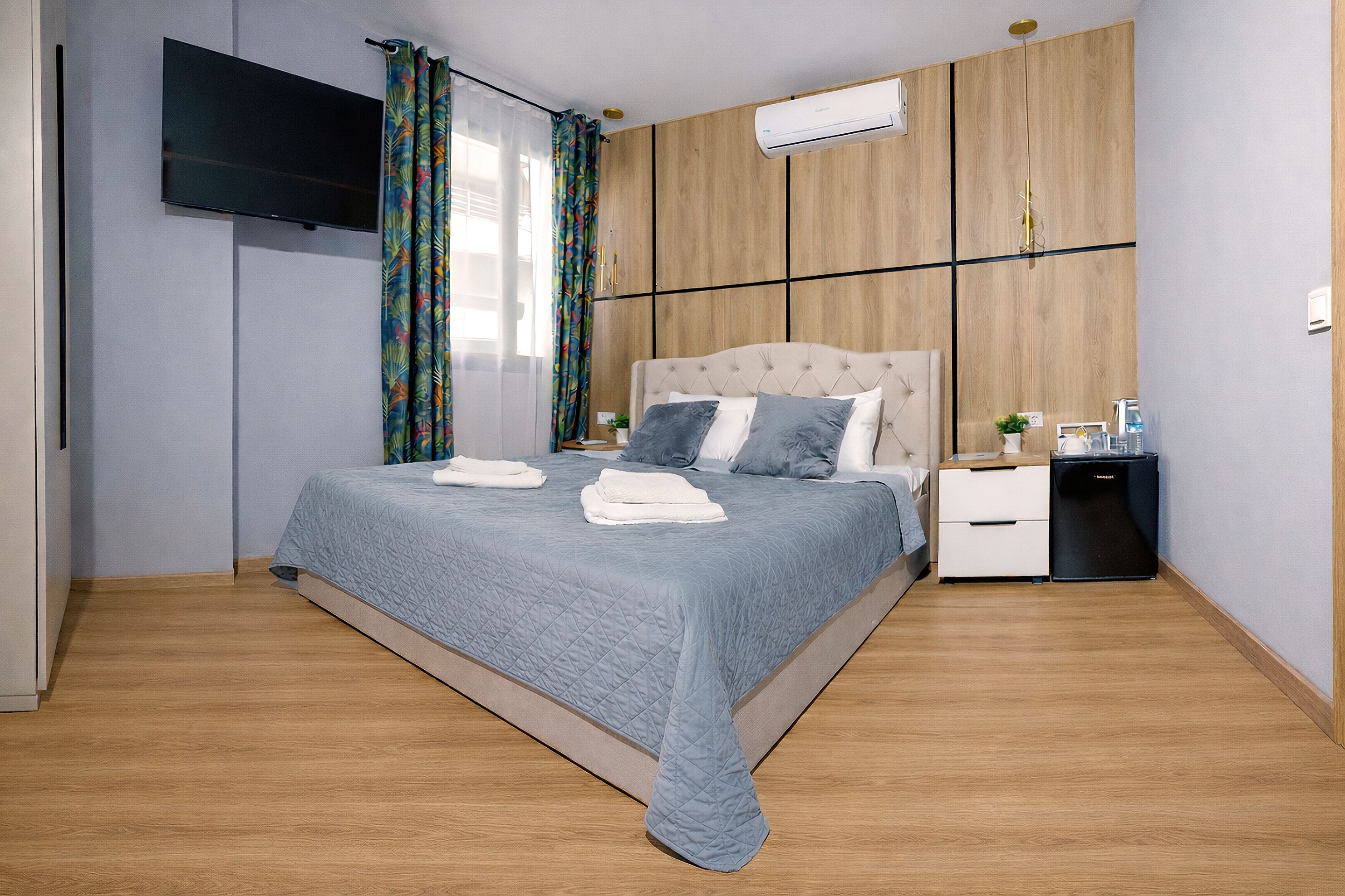 Een slaapkamer met een bed, een televisie, een nachtkastje en een airconditioning.