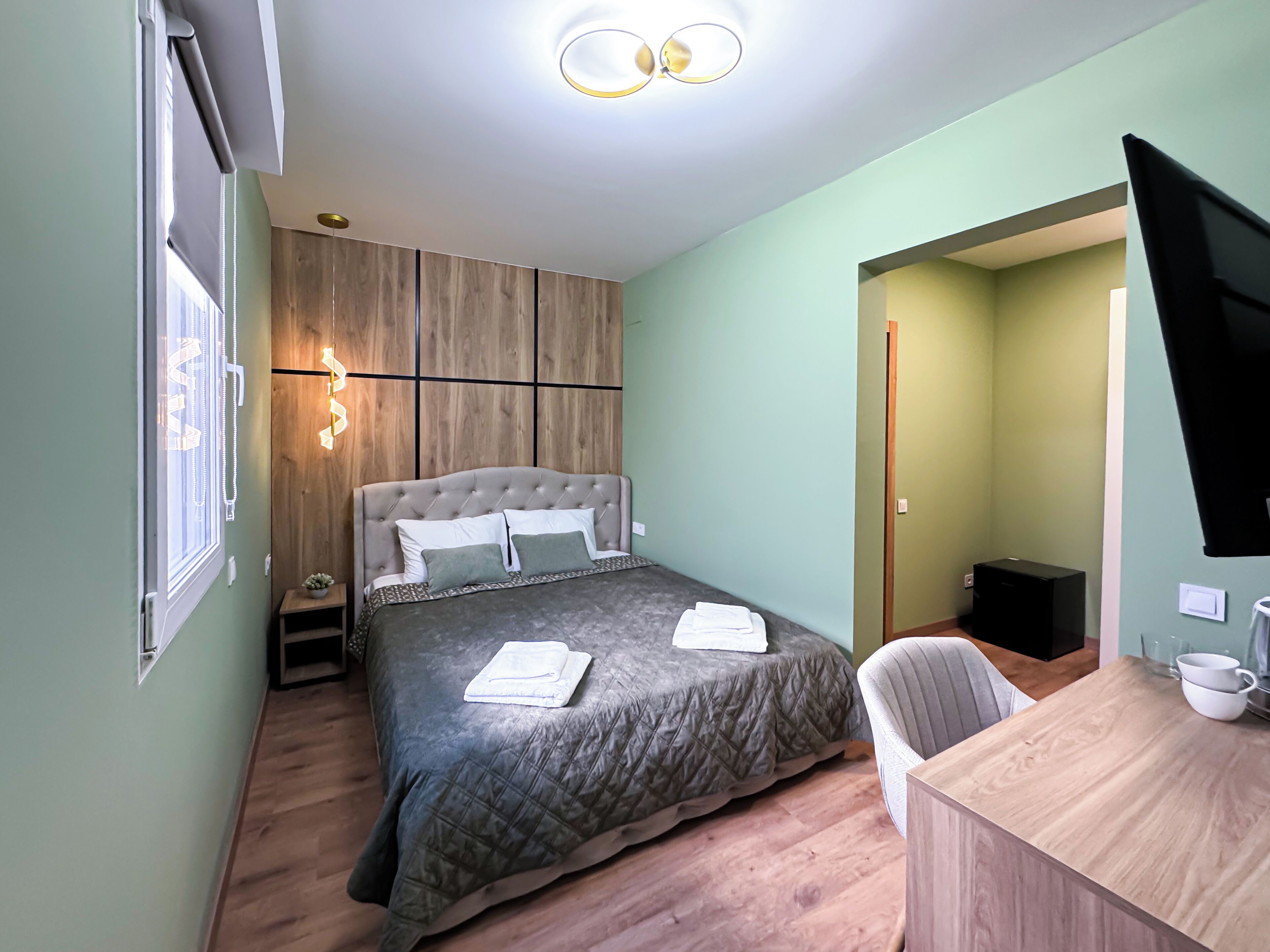 A bedroom with a bed, bedside table, and a desk with a chair.