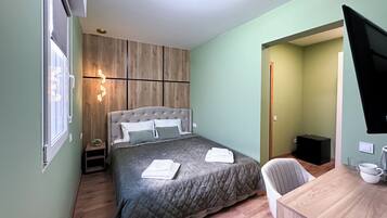 A bedroom with a bed, bedside table, and a desk with a chair.