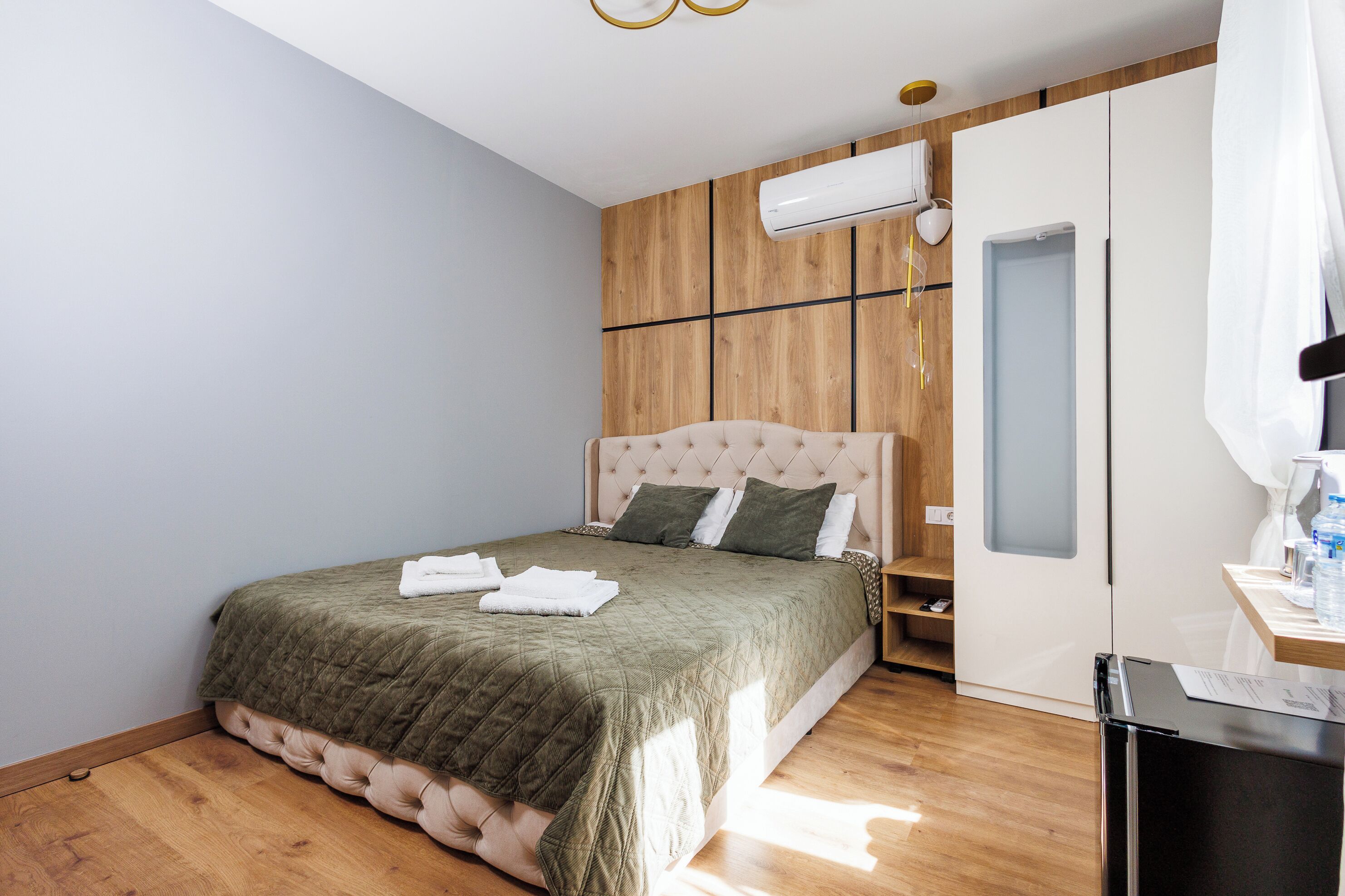 Une chambre à coucher avec un lit, un mur recouvert de panneaux en bois, une armoire blanche et un petit bureau avec un miroir.