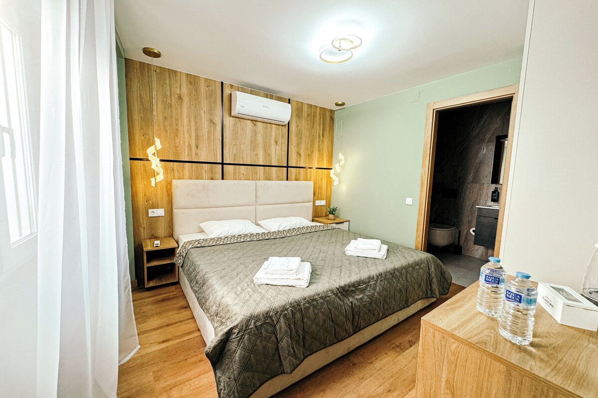 A hotel room with a bed, bedside table, and a wooden headboard.