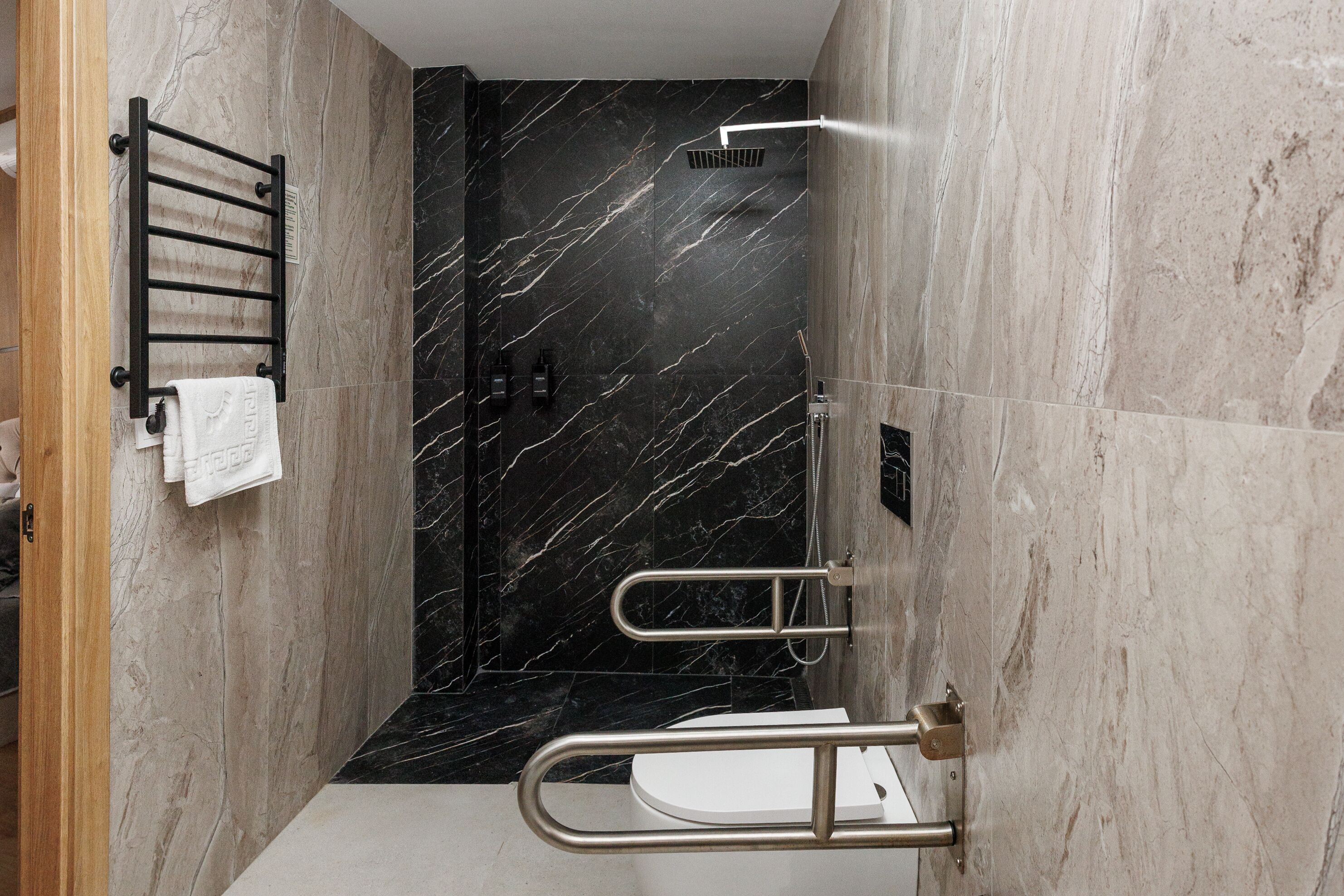 A modern bathroom with a shower, a towel rack, and a toilet.