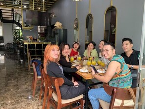 Un grupo de personas sentadas alrededor de una mesa en un comedor moderno con una escalera y decoración de estilo industrial.