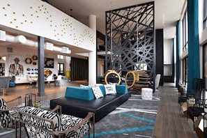 A modern hotel lobby with a black and white patterned sofa, a geometric wall design, and a variety of seating options. - Landing Apartments Downtown Arlington (Arlington)