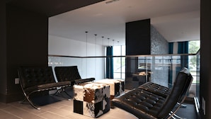 Un intérieur moderne avec des fauteuils en cuir, une table en verre et une vue sur l’extérieur.