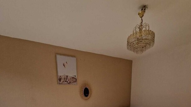 Ein Hotelzimmer mit drei Einzelbetten, einer Kristallleuchtre, einer Wanduhr und einem gerahmten Bild.