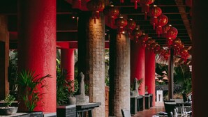 A spacious indoor area with high ceilings, red pillars, and hanging red lanterns. Tables and chairs are arranged for dining. - Elegant Seibal Penthouse - Vidanta (Nuevo Vallarta)
