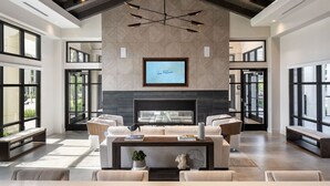 Un salón amplio con techo alto, muebles modernos y ventanas grandes.
