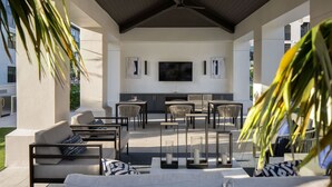 Un patio exterior con una televisión de pantalla plana montada en la pared, rodeado de asientos y una chimenea empotrada.