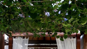 A bed under a canopy with white curtains, a blue bedspread, and two pillows. - SPV 8008 · LUXURY JIMBARAN VILLA BY THE BEACH (Bali)