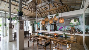 Een ruime keuken met een groot kookeiland, houten stoelen, hangende lampen en diverse keukenapparaten.
