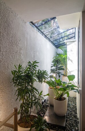 A narrow indoor corridor with potted plants and a wooden chair. - MariJo Villa·2BR Private Pool mins to Central Ubud (Bali)