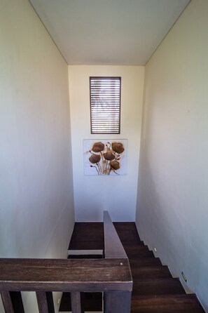 A staircase with wooden steps leading upwards, flanked by plain walls and a window with blinds. - MariJo Villa·2BR Private Pool mins to Central Ubud (Bali)