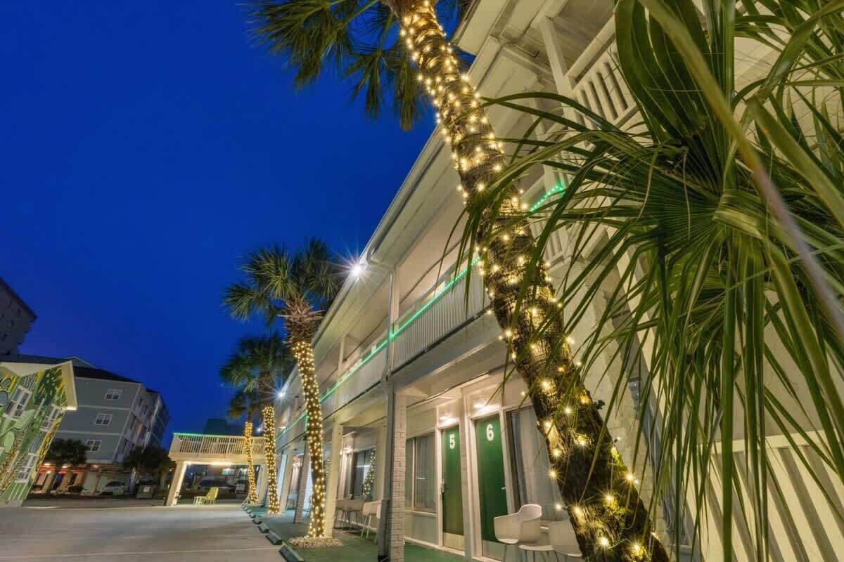 Un hotel amb diverses plantes, cadascuna amb portes numerades, i una palmera decorada amb llums.