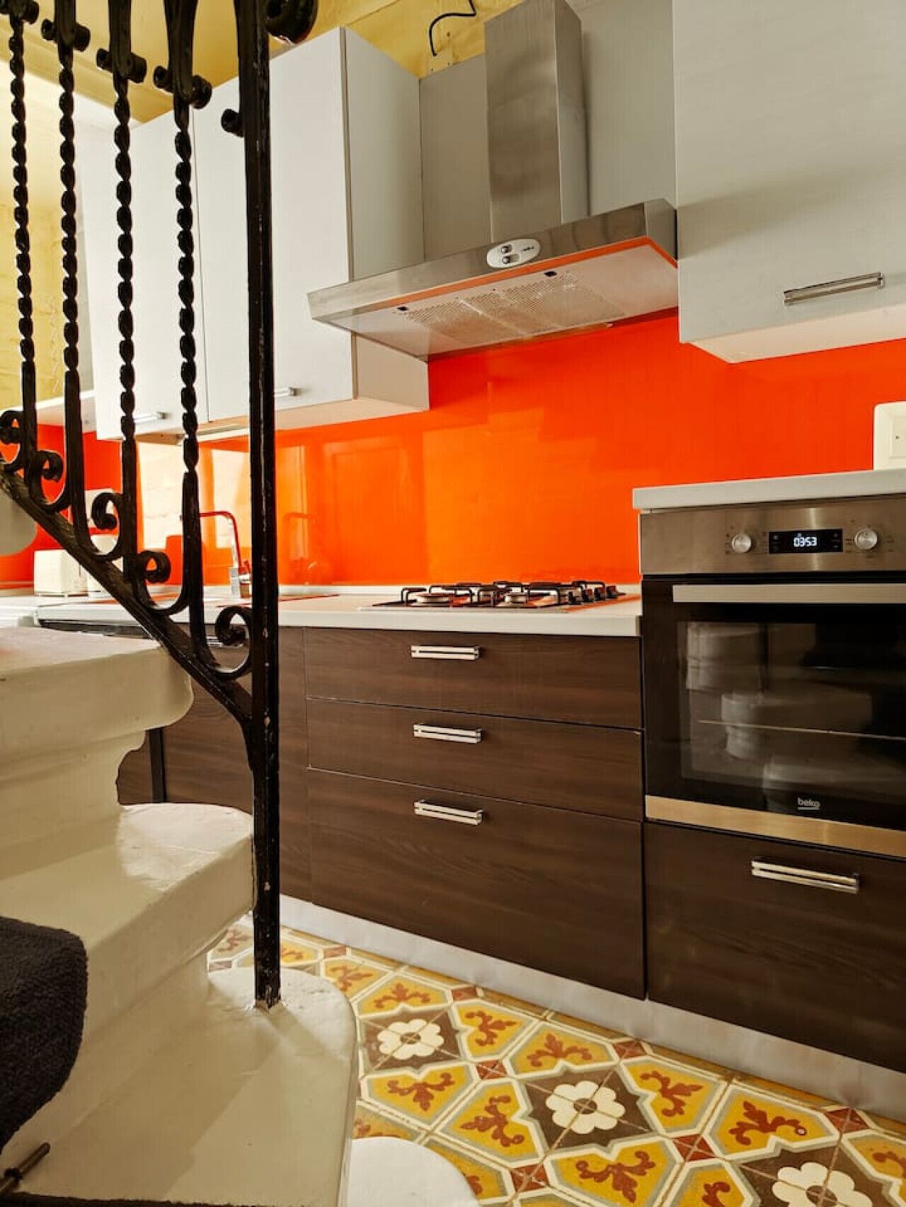A kitchen with a modern design, featuring a gas stove, oven, and a stainless steel range hood.